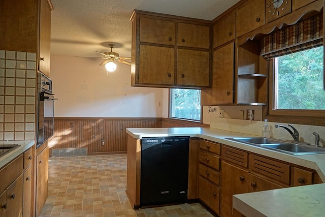 kitchen with a healthy amount of sunlight, black appliances, kitchen peninsula, and wooden walls