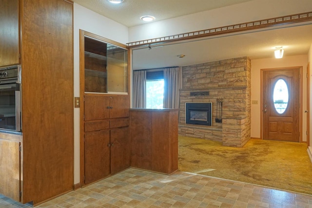 carpeted entryway with a textured ceiling and a fireplace