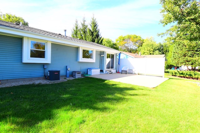 rear view of house with central AC unit, a patio area, and a yard