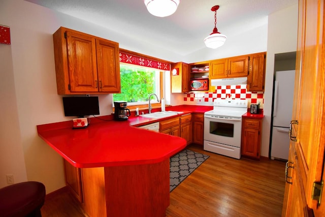 kitchen featuring pendant lighting, kitchen peninsula, sink, white appliances, and hardwood / wood-style flooring