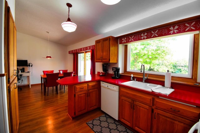 kitchen featuring white dishwasher, hanging light fixtures, kitchen peninsula, and plenty of natural light