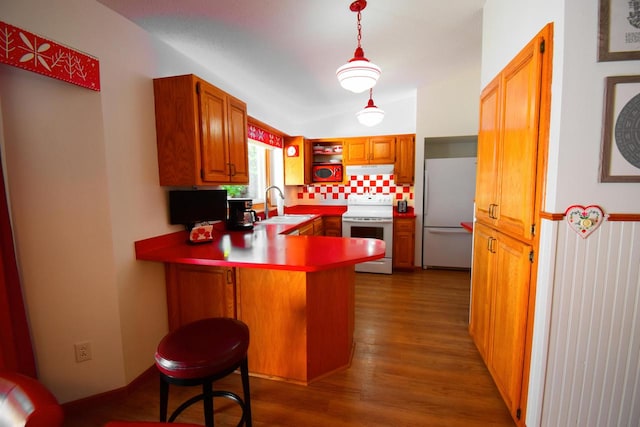 kitchen with pendant lighting, kitchen peninsula, white appliances, a breakfast bar, and dark hardwood / wood-style flooring