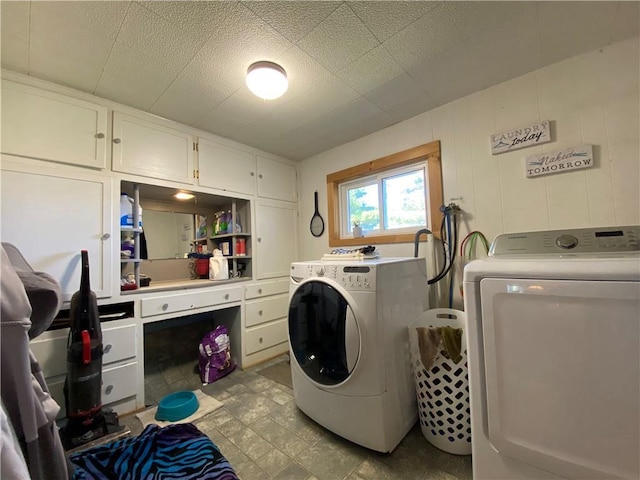 clothes washing area featuring separate washer and dryer, cabinets, and wooden walls