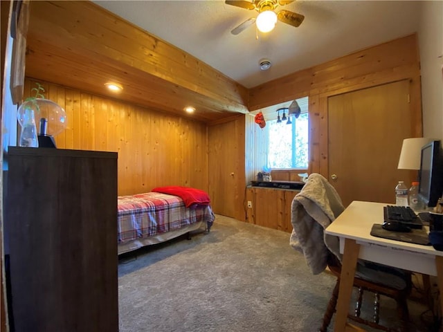 bedroom with wood walls, ceiling fan, and carpet flooring