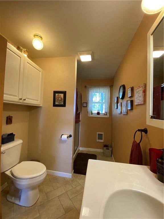 bathroom with vanity, lofted ceiling, tile patterned floors, toilet, and a shower with door