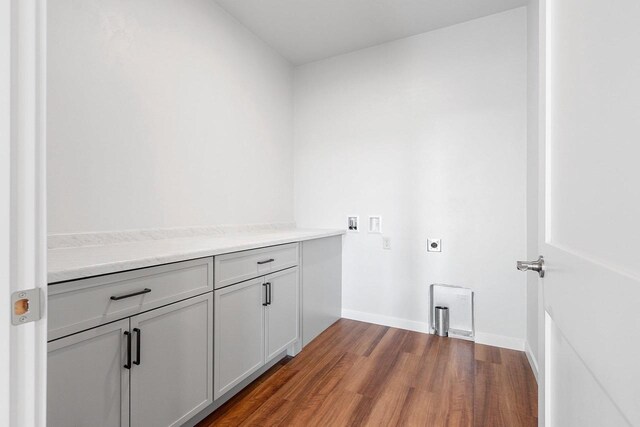 laundry area featuring electric dryer hookup, washer hookup, hardwood / wood-style flooring, and cabinets