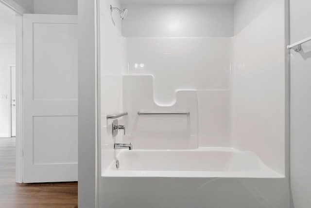 bathroom with hardwood / wood-style flooring and bathing tub / shower combination