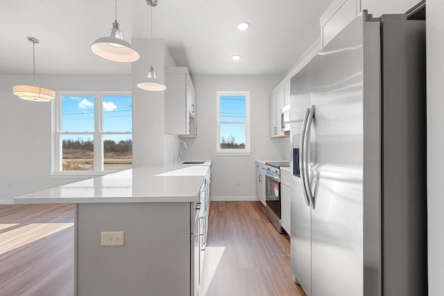 kitchen with white cabinetry, appliances with stainless steel finishes, and pendant lighting