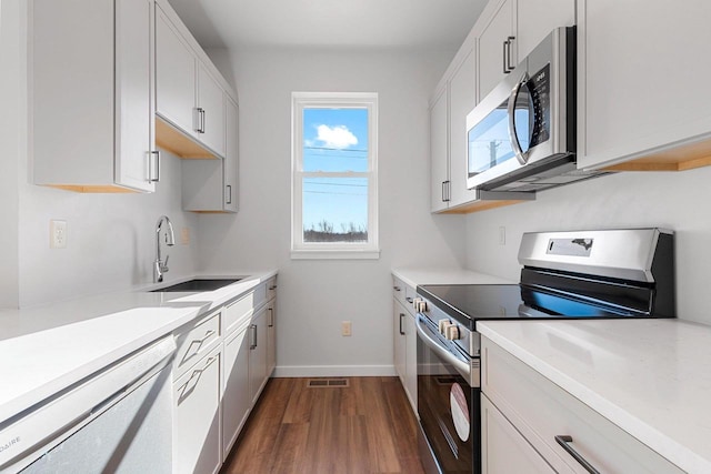 kitchen featuring dark hardwood / wood-style flooring, sink, white cabinets, and appliances with stainless steel finishes