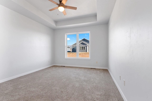 unfurnished room featuring ceiling fan, carpet flooring, and a tray ceiling