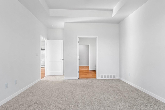 unfurnished bedroom with a raised ceiling and carpet