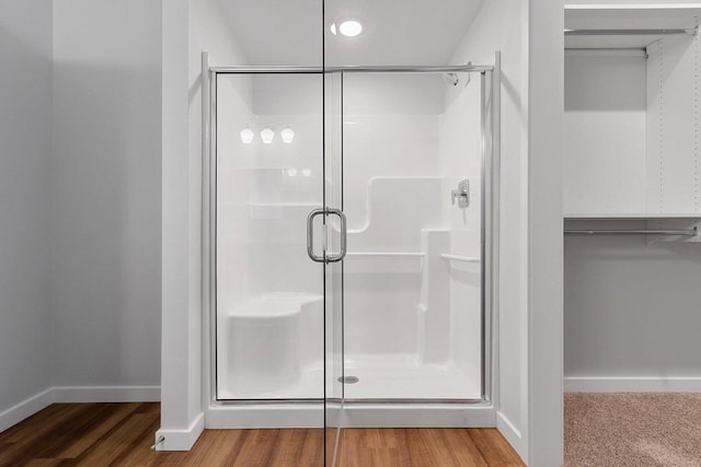 bathroom with a shower with shower door and hardwood / wood-style floors