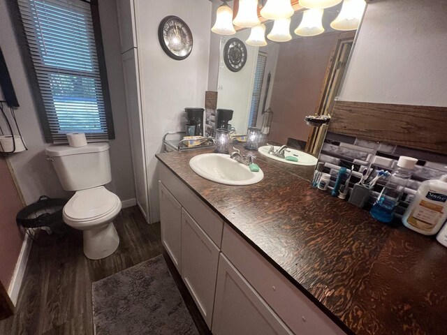 650 Roosevelt St, Mauston, WI 53948 - bathroom with wood finished floors, vanity, a chandelier, baseboards, and toilet