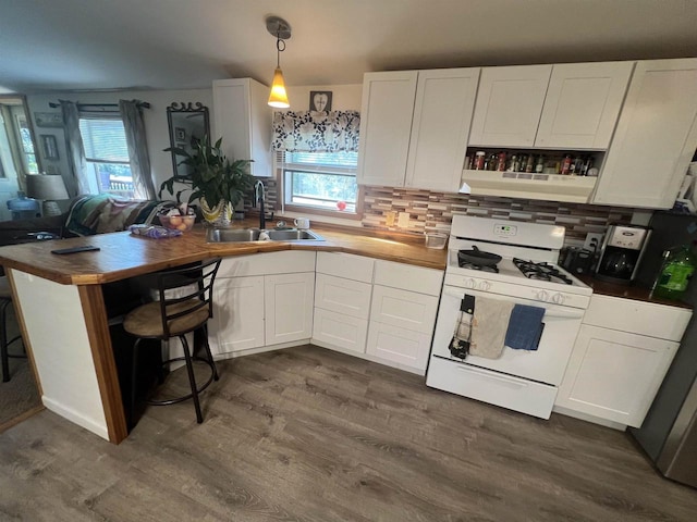 kitchen with butcher block countertops, sink, gas range gas stove, and white cabinetry