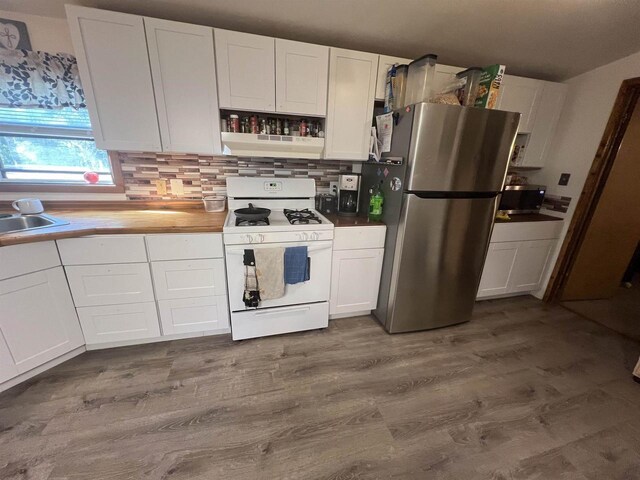 650 Roosevelt St, Mauston, WI 53948 - kitchen featuring white cabinets, gas range gas stove, tasteful backsplash, freestanding refrigerator, and dark wood-type flooring