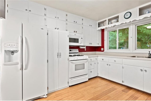 kitchen with sink, light hardwood / wood-style floors, white cabinetry, and white appliances