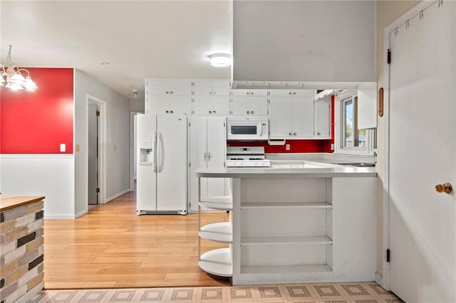 kitchen featuring light hardwood / wood-style floors, a breakfast bar area, a chandelier, white cabinetry, and white appliances