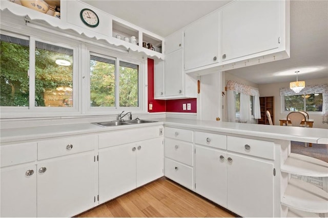 kitchen with light hardwood / wood-style floors, white cabinets, and sink