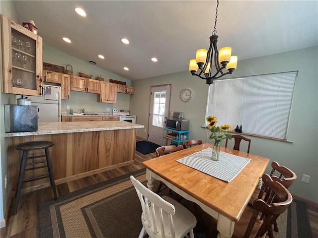 dining area with an inviting chandelier, lofted ceiling, dark hardwood / wood-style floors, and sink