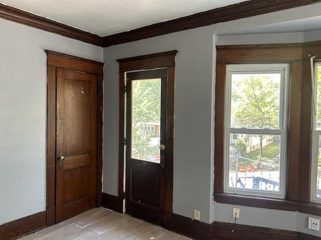 entryway with light wood-type flooring and ornamental molding