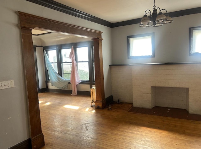 spare room with light hardwood / wood-style flooring, a chandelier, plenty of natural light, and a fireplace