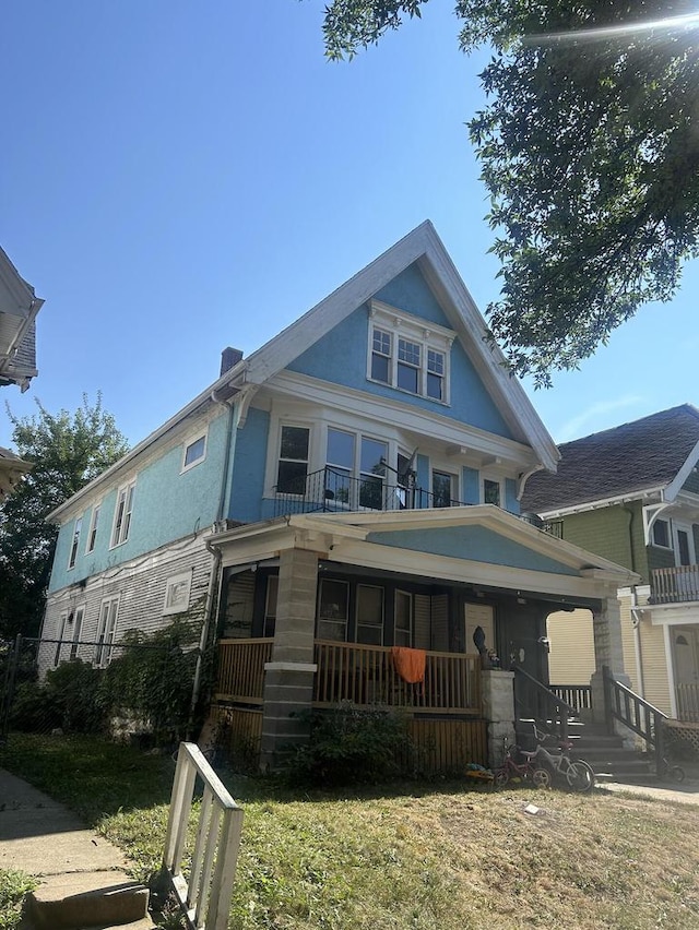 view of front facade with a front yard, a balcony, and a porch