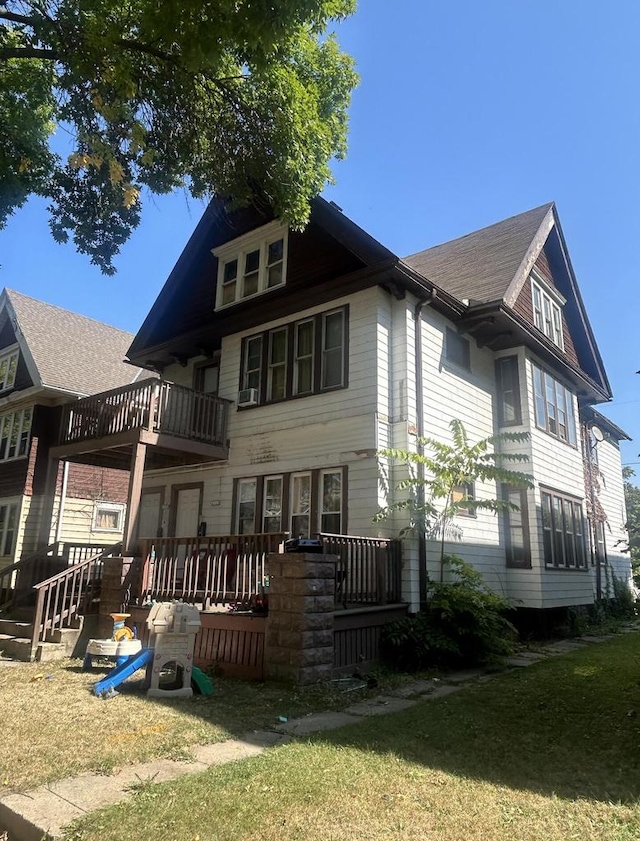 back of house featuring cooling unit, a balcony, and a yard