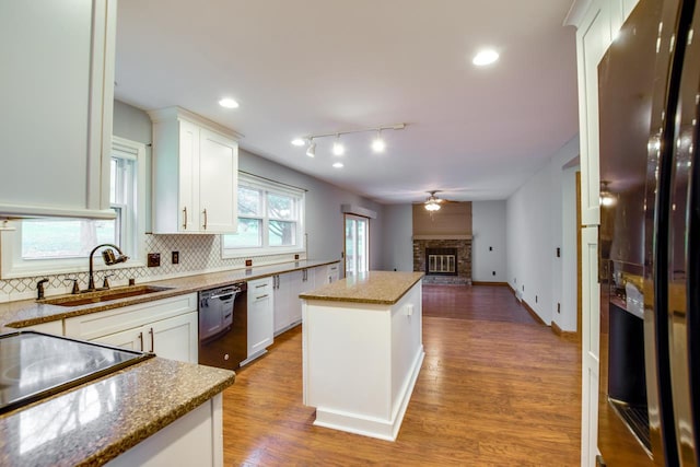 kitchen with a kitchen island, black fridge, sink, and white cabinets