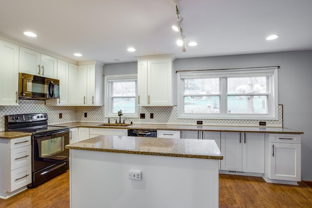 kitchen featuring hardwood / wood-style floors, white cabinetry, black appliances, and a center island