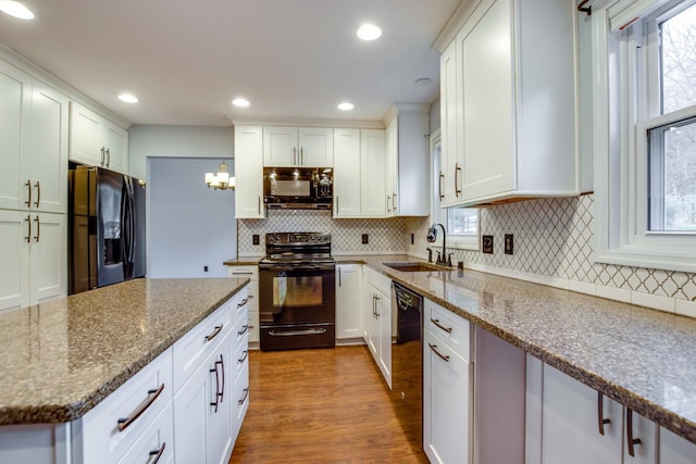 kitchen with white cabinets, hardwood / wood-style floors, black appliances, sink, and light stone countertops