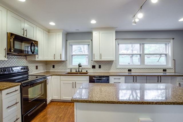 kitchen featuring light hardwood / wood-style floors, sink, black appliances, tasteful backsplash, and light stone countertops