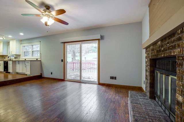 unfurnished living room with a fireplace, a healthy amount of sunlight, and dark hardwood / wood-style flooring