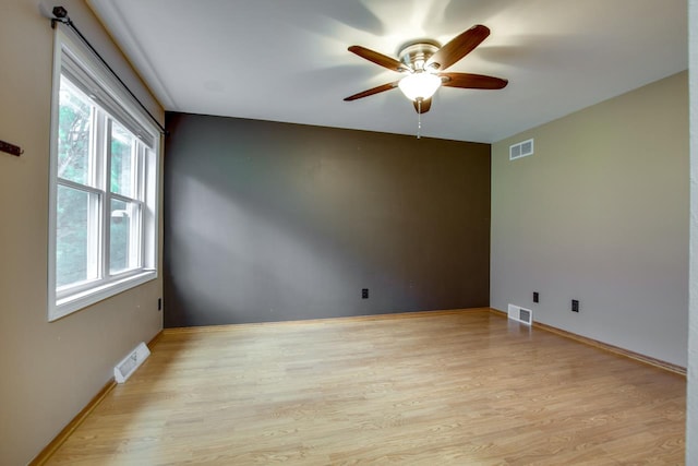 spare room featuring a wealth of natural light, light hardwood / wood-style floors, and ceiling fan