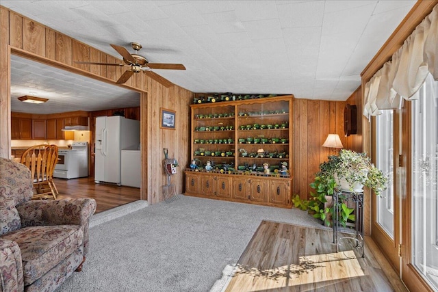 living room featuring ceiling fan, wood walls, and hardwood / wood-style floors