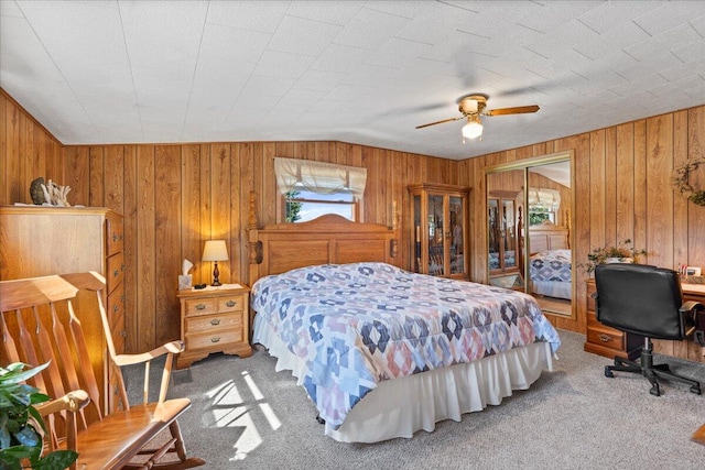 bedroom featuring ceiling fan, carpet flooring, wood walls, and vaulted ceiling