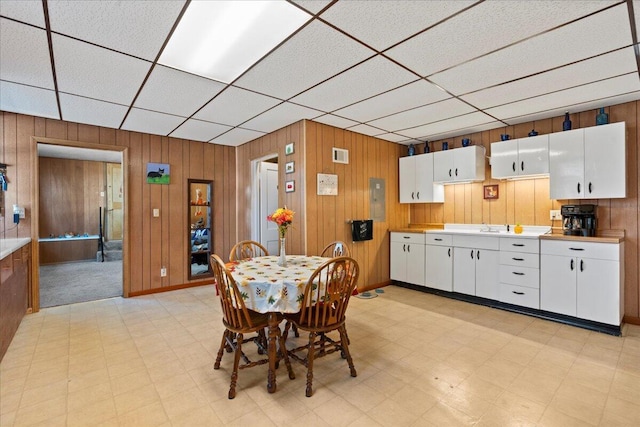 dining room with wooden walls and a drop ceiling