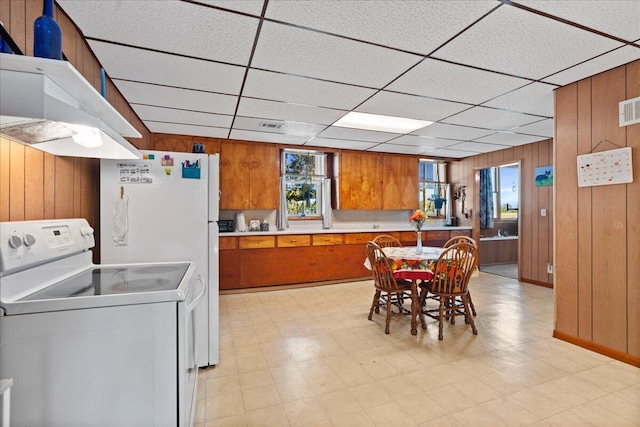 kitchen featuring exhaust hood, white electric range oven, a drop ceiling, and wood walls