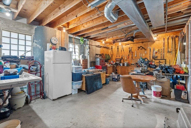 basement with white fridge and a workshop area