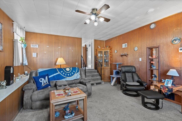 carpeted living room featuring ceiling fan and wooden walls