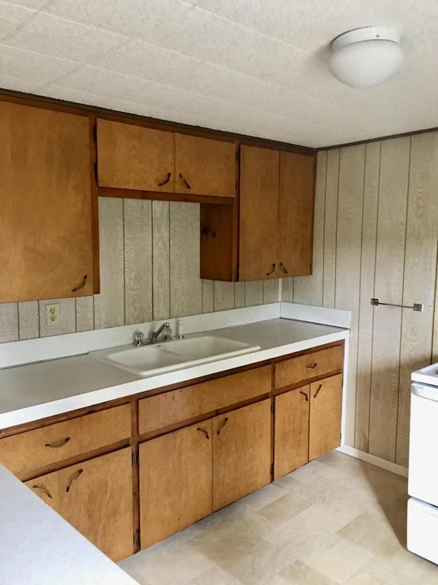 kitchen with white range, wood walls, and sink