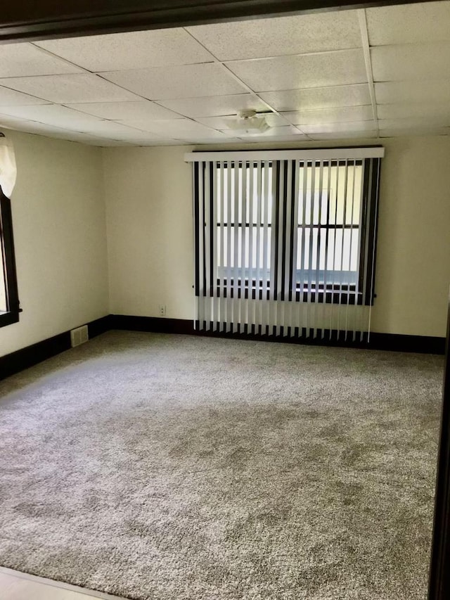 carpeted empty room with a paneled ceiling