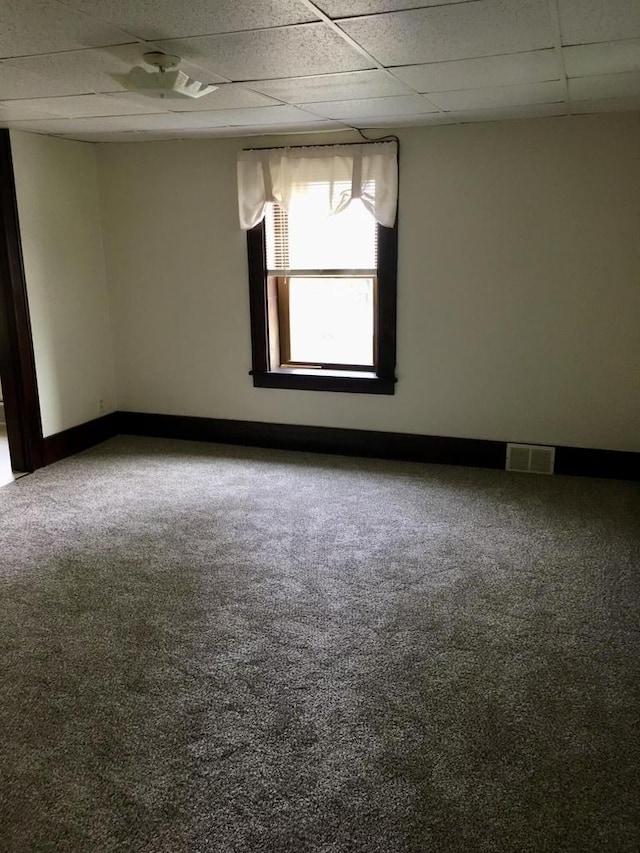 spare room featuring a paneled ceiling and carpet flooring