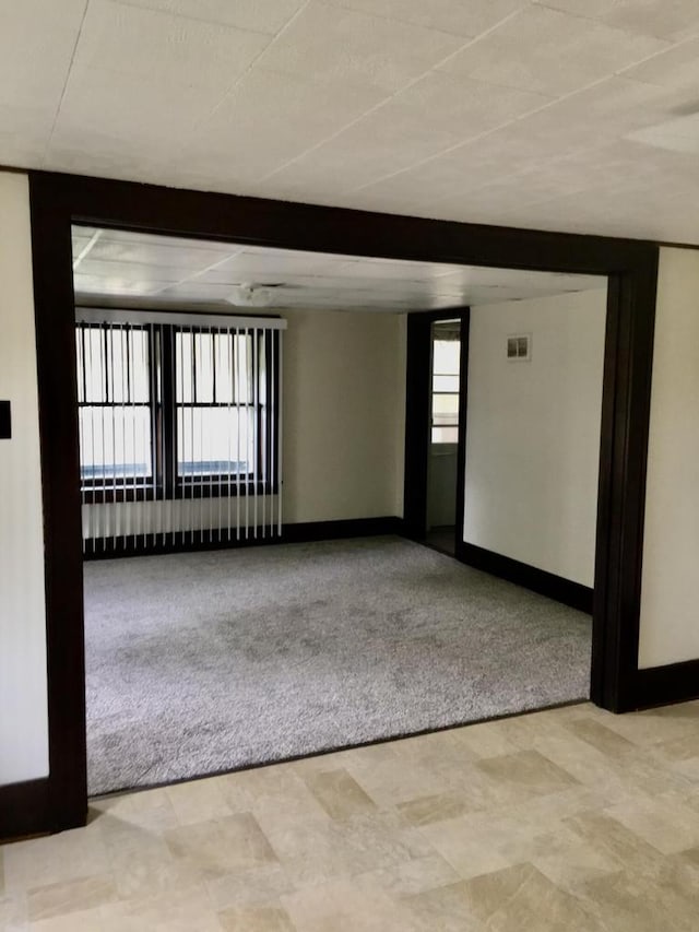 carpeted empty room with beamed ceiling and a healthy amount of sunlight