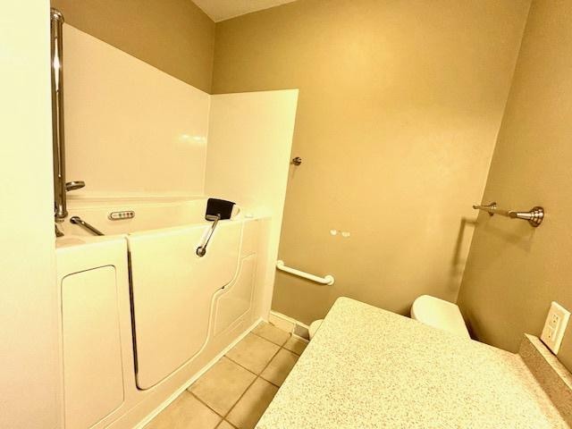 bathroom with tile patterned flooring, toilet, and a bathing tub