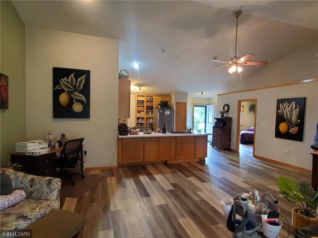 kitchen with wood-type flooring, lofted ceiling, kitchen peninsula, stainless steel refrigerator, and ceiling fan