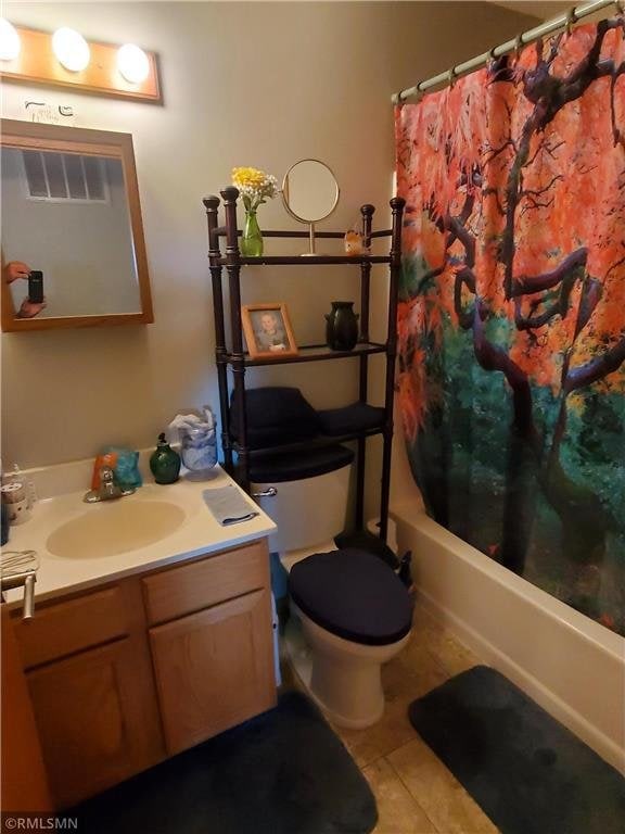 full bathroom with shower / tub combo with curtain, vanity, toilet, and tile patterned floors