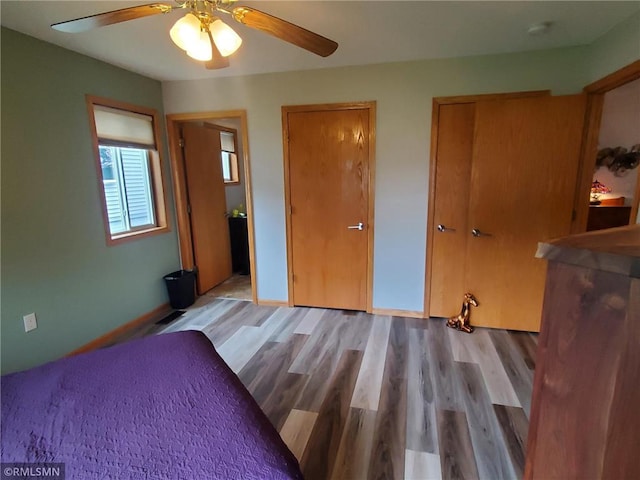 bedroom with light wood-type flooring, multiple closets, and ceiling fan