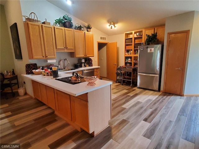 kitchen with appliances with stainless steel finishes, sink, lofted ceiling, and light hardwood / wood-style flooring