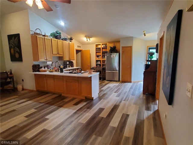 kitchen featuring ceiling fan, kitchen peninsula, hardwood / wood-style floors, and stainless steel refrigerator