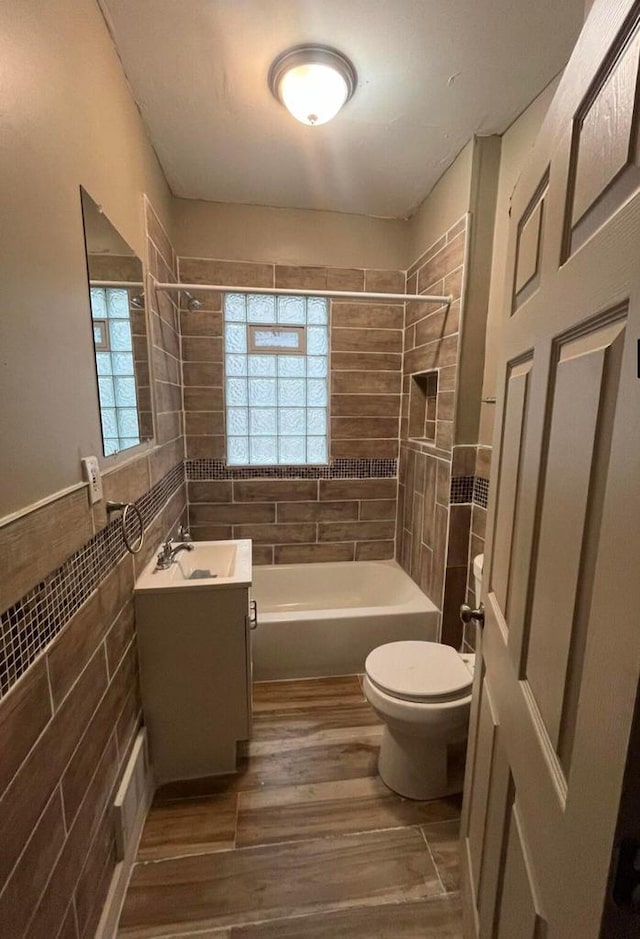 full bathroom featuring a wealth of natural light, vanity, toilet, and tiled shower / bath